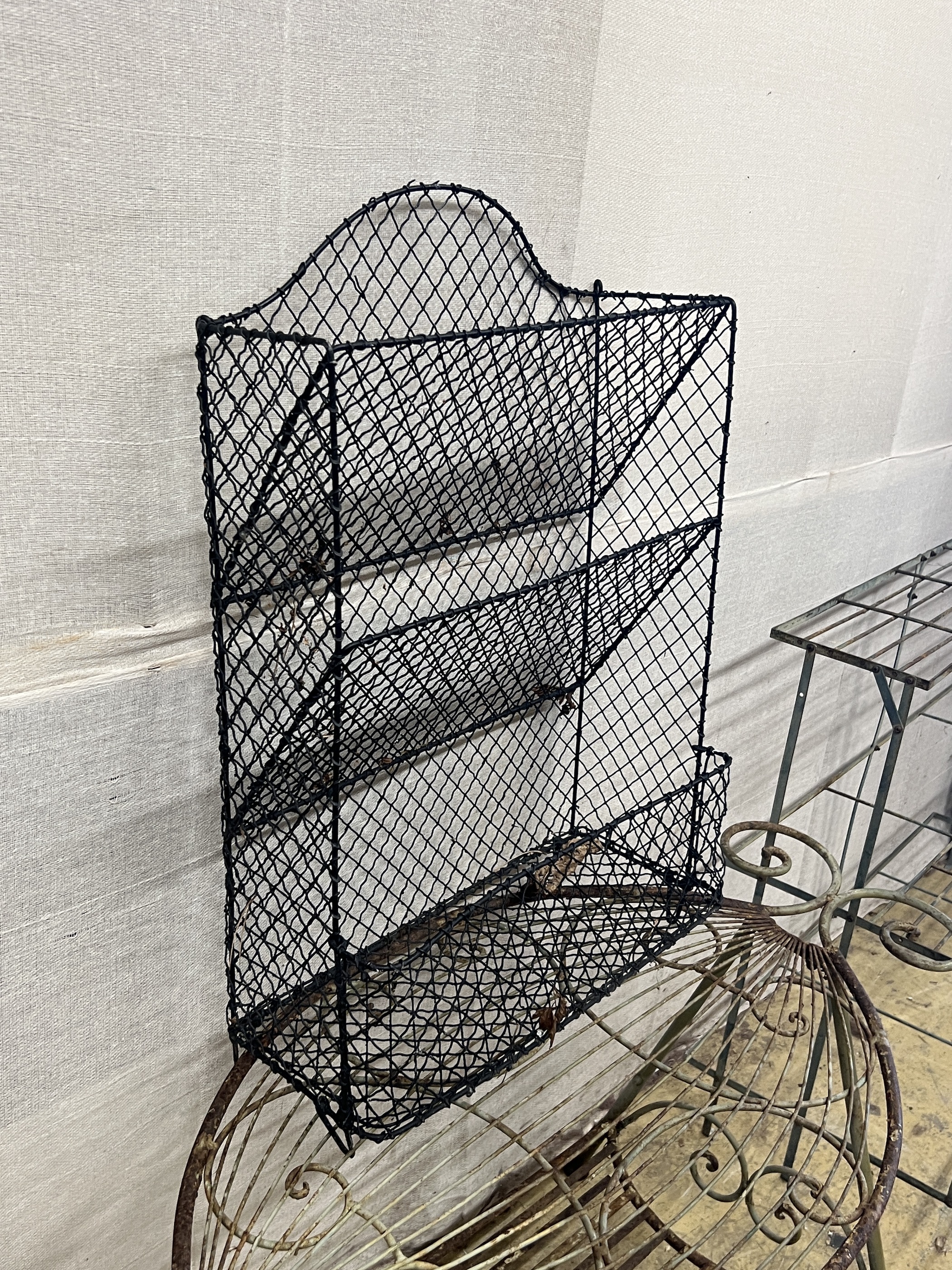 A painted wrought iron three tier pot stand, width 100cm, together with an oval wrought iron garden table and a three tier rack
